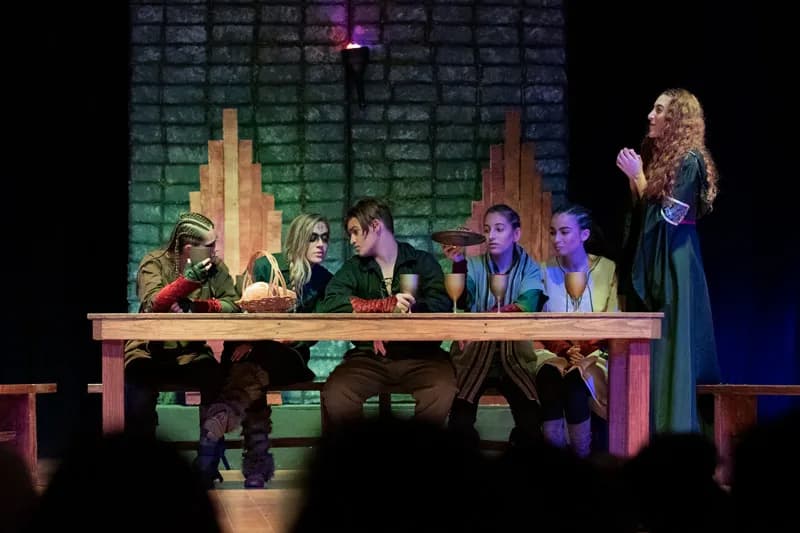 Students sitting on a table while dressed up in their customs 